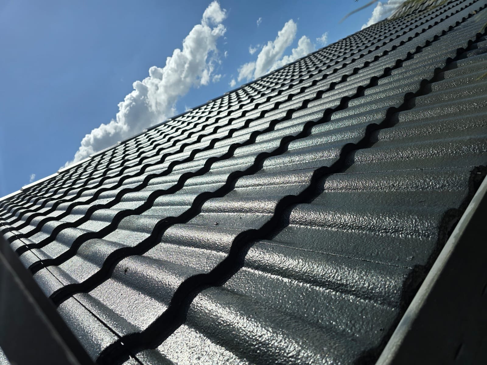 Close-up of modern grey metal roof tiles under blue sky